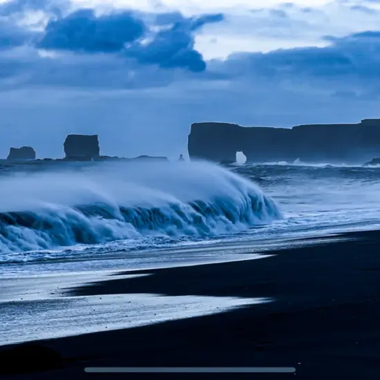 Black Sand Beach near Vík with the Dyrhólaey rock arch and other basalt stacks on the horizon